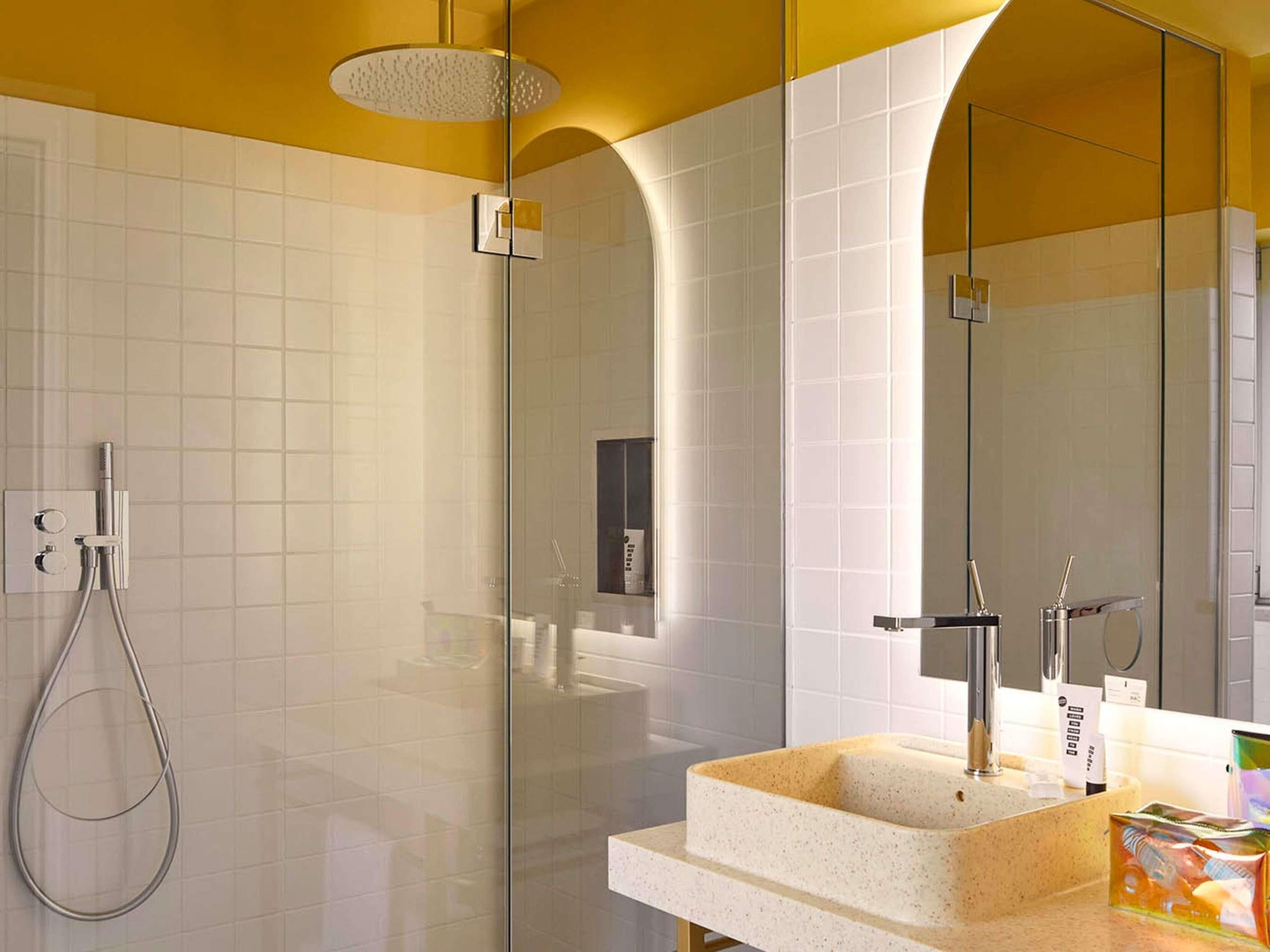 Une salle de bain moderne avec une douche à parois de verre, un lavabo sur pied et un grand miroir.