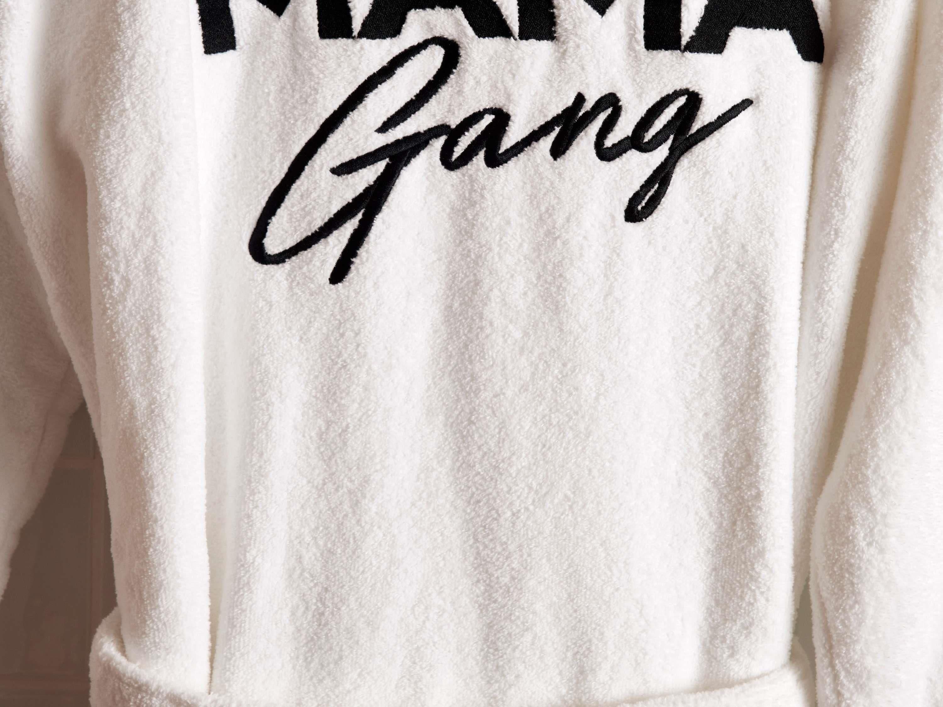 Un asciugamano bianco con la scritta 'Mama Gang' ricamata in nero.