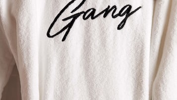 Un asciugamano bianco con la scritta 'Mama Gang' ricamata in nero.