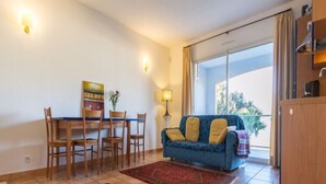 A living room with a sofa, a dining table with chairs, and a coffee table. There is a large window with curtains, a lamp, and a painting on the wall. - Residence with sea view (propiano)