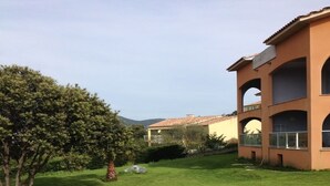 A well-maintained lawn with a large tree and a building with multiple balconies. - Residence with sea view (propiano)