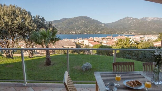 A terrace with a table set for breakfast, overlooking a scenic view of a coastal town and mountains. - Residence with sea view (propiano)