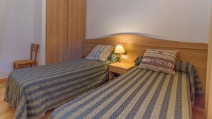 A room with two single beds, a nightstand with a lamp, a wooden wardrobe, and a chair. - Residence with sea view (propiano)