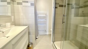 Un bagno moderno con cabina doccia in vetro, un lavandino bianco e un porta asciugamani.