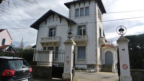 Un edificio a due piani con un balcone, un cancello e un lampione.
