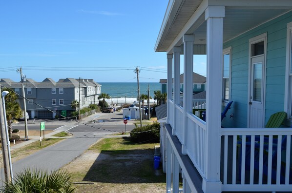 A coastal house with a porch overlooking the ocean.