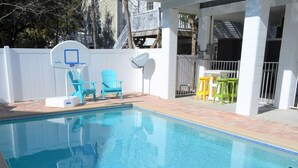 A swimming pool with a basketball hoop, blue and green chairs, and a satellite dish. - Moana & Ohana - Walk to beach in Surfside Beach, SC (Surfside Beach)