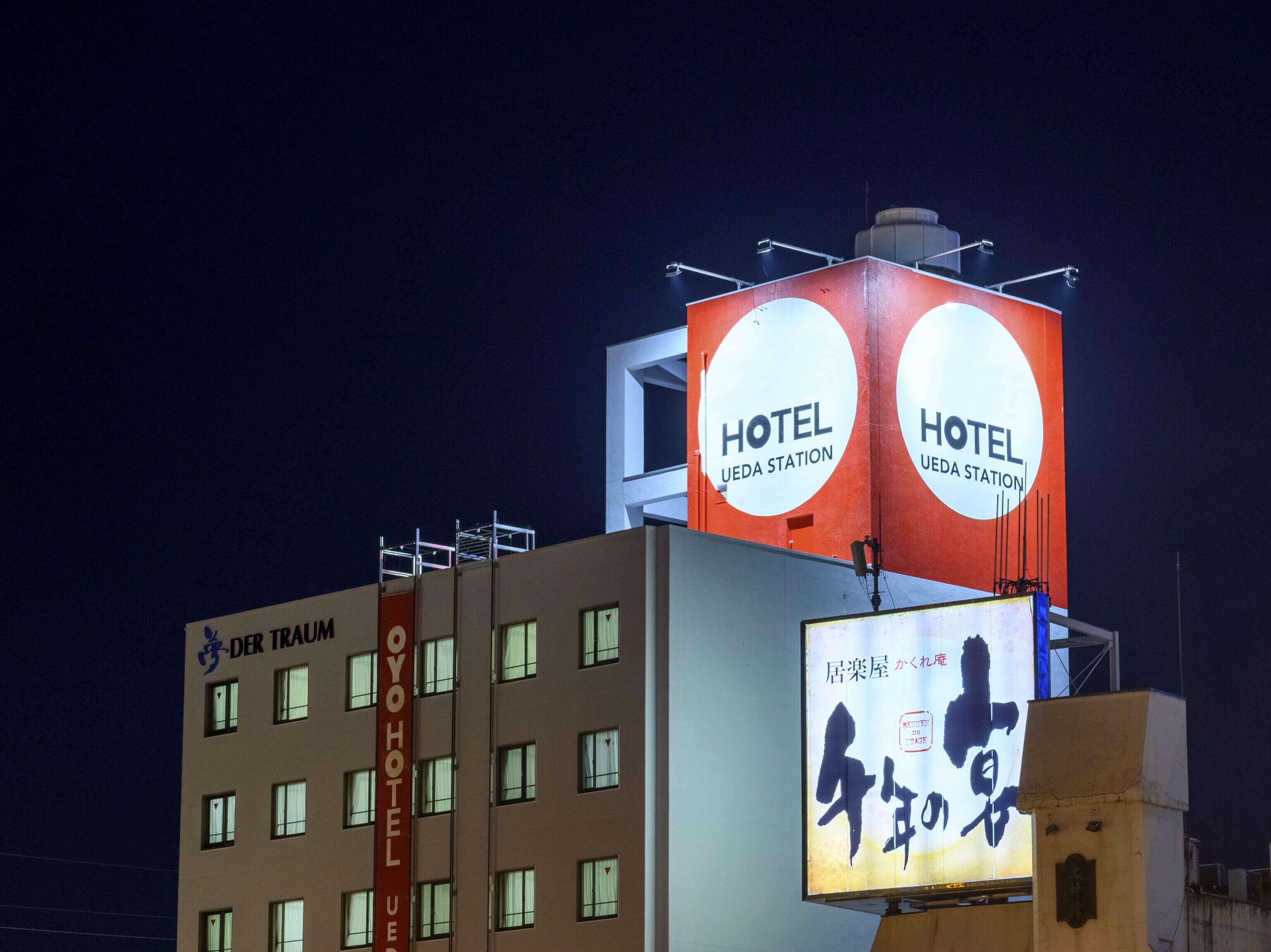 A hotel with signage indicating 'HOTEL UEDA STATION' and a sign with Japanese characters.
