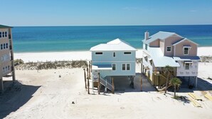 Ein Strandgrundstück mit einem zweistöckigen Haus, einem separaten Gebäude und einem Strandabschnitt mit Sand.