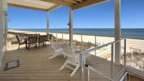 Eine Holzterrasse mit Blick auf Strand und Meer.