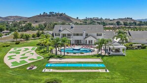 A large, two-story house with a swimming pool, surrounded by a well-maintained lawn and palm trees. - * NEW Luxury Celebrity Vineyard Estate Temecula * (Murrieta)