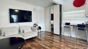 En moderne stue med sofa, sofabord og spiseområde med stole.