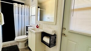 Et badeværelse med toilet, vask, spejl og håndklædestang.