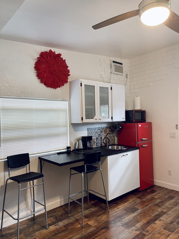 A compact kitchen with a black countertop, white cabinets, a red refrigerator, and a ceiling fan. - ❤️Red flower (Where you are welcome) (Largo)