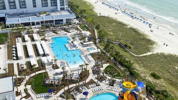 Ein Resort mit mehreren Schwimmbecken, einem Wasserpark und einem Strand.