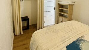 Ett sovrum med en säng, en takfläkt, en garderob och ett litet bord.