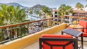 Un balcón con vista a un puerto deportivo, palmeras y una montaña a lo lejos.