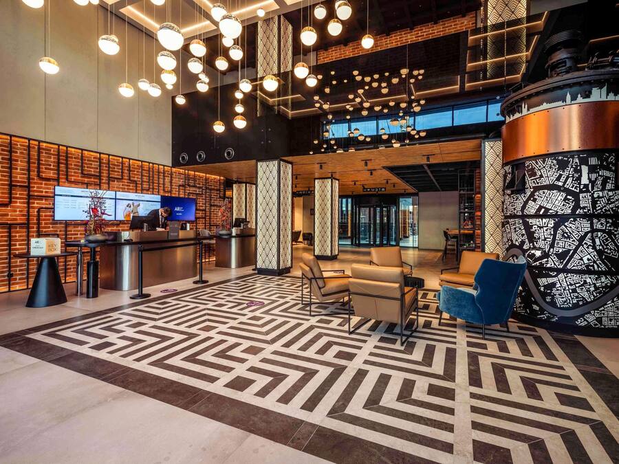 A modern lobby with a reception desk, seating area, and a patterned floor.