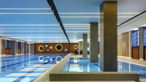 Una piscina interior moderna con vistas claras al área de la piscina, un espacio de descanso y una pared con luminarias circulares.
