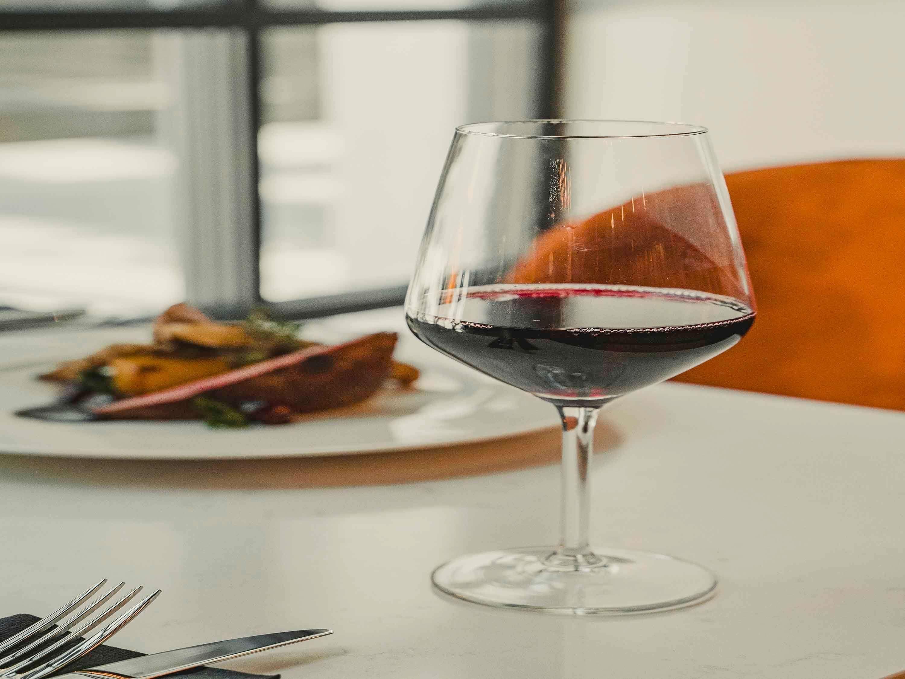 A wine glass with red wine on a table.