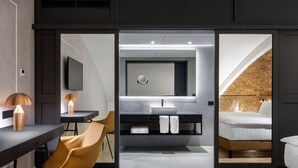 Una habitación de hotel moderna con escritorio, silla y un espejo grande.