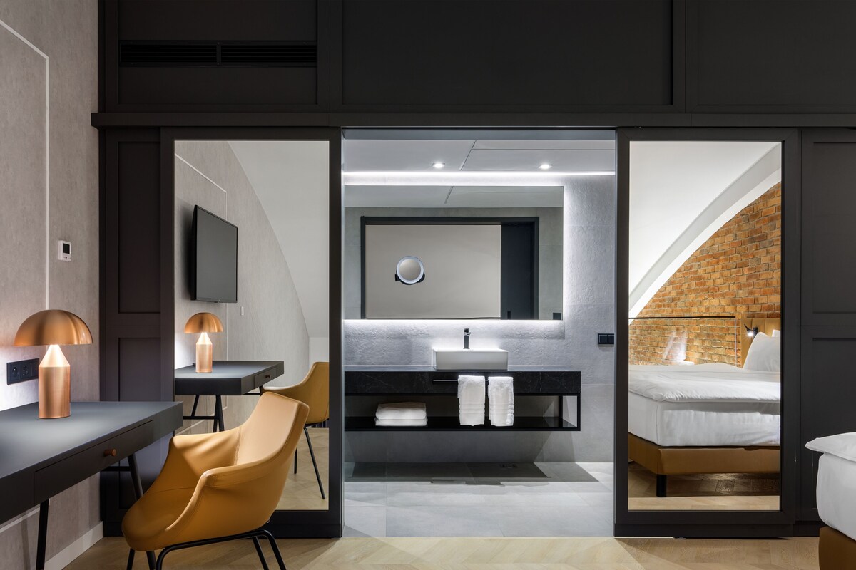 Una habitación de hotel moderna con escritorio, silla y un espejo grande.