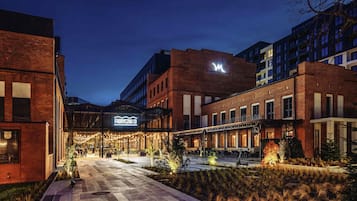Hotel de diseño moderno, con fachadas de ladrillo y vidrio, un área exterior bien iluminada con asientos y un cartel llamativo del hotel.