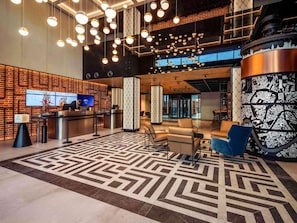 Un hall dâentrĂ©e moderne avec un comptoir dâaccueil, un espace salon et un sol Ă motifs.