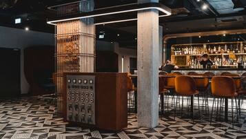 A bar area with a patterned floor, a bar counter, and a bartender.