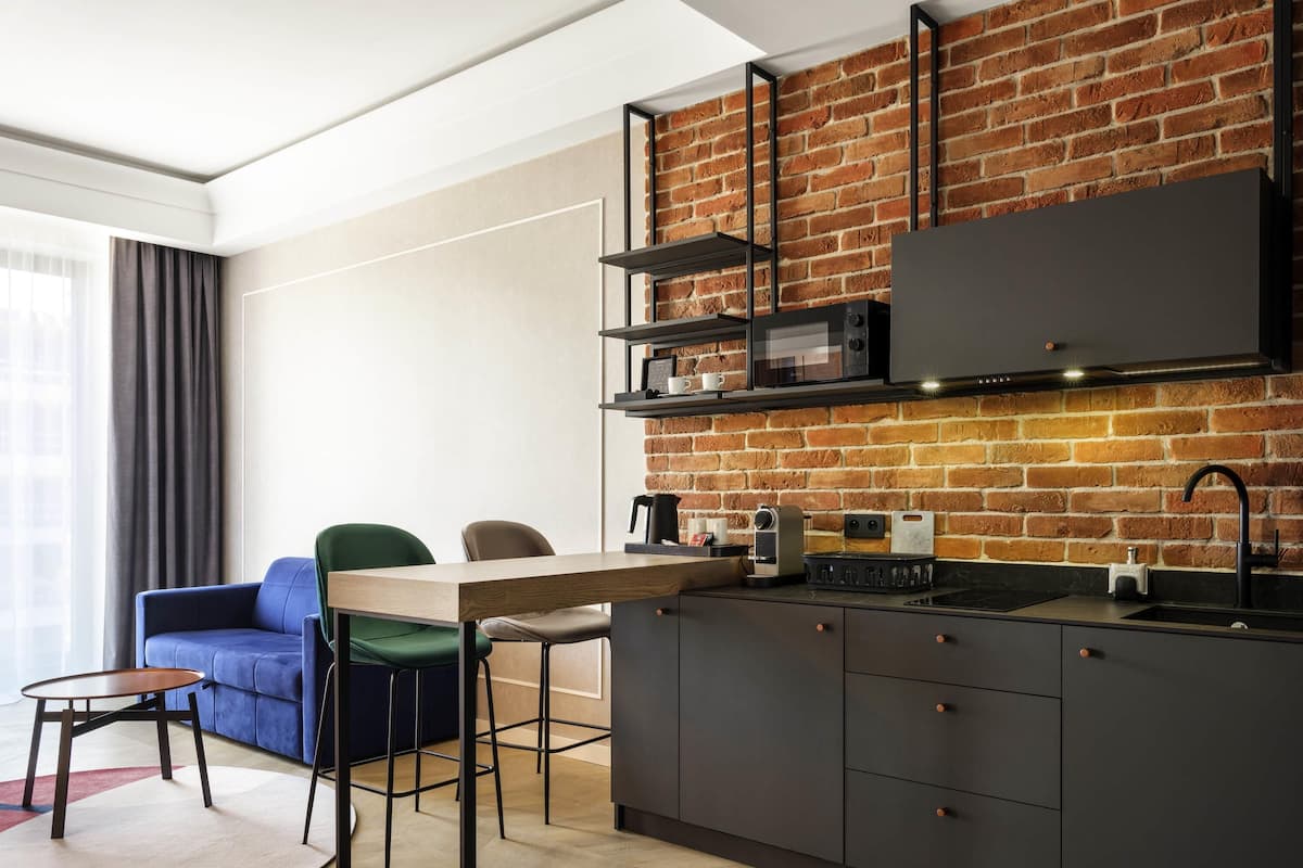 Una cocina moderna con pared de ladrillo, una mesa de comedor con sillas y un sofá en una sala de estar.