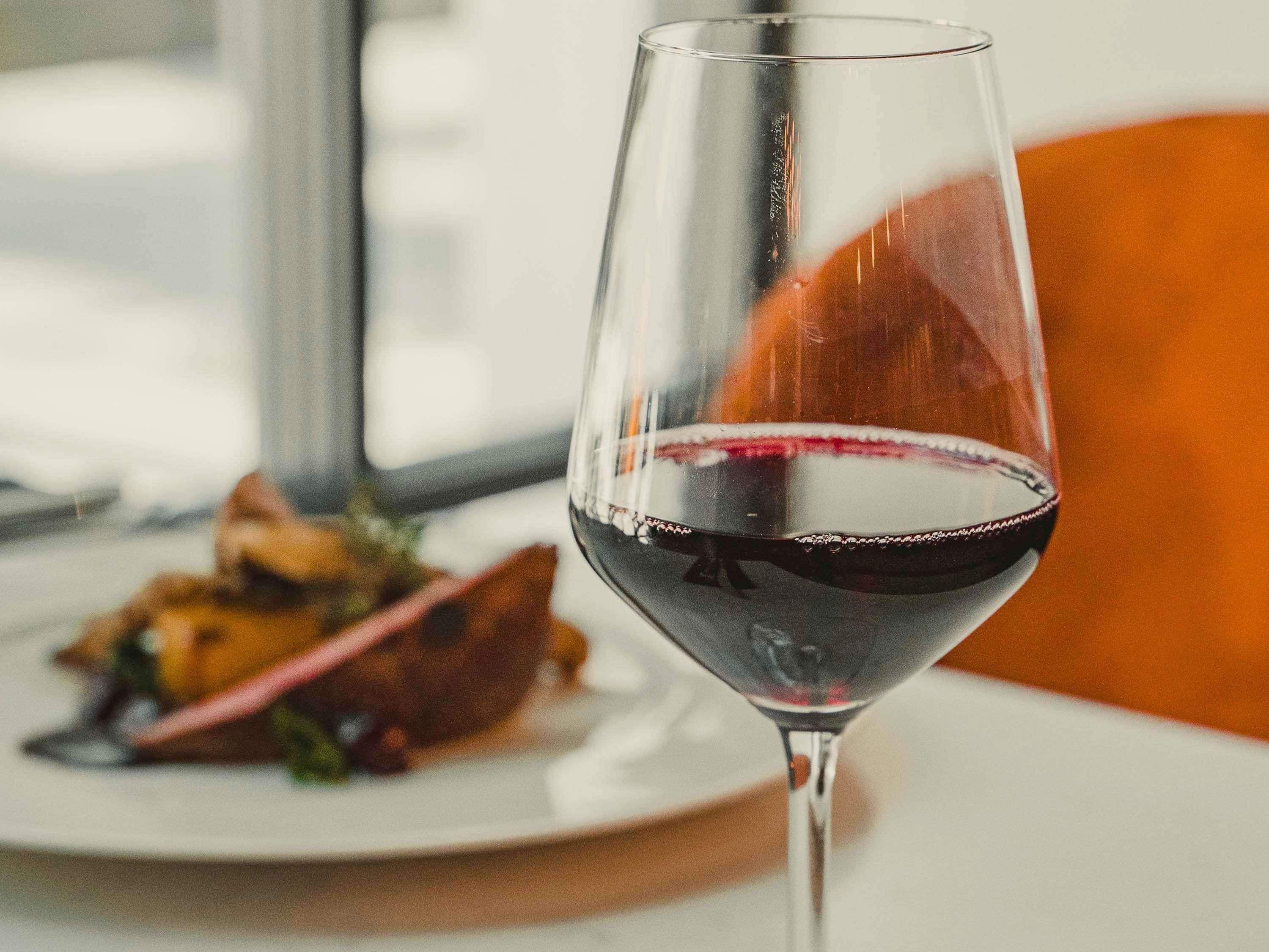 A wine glass with red wine on a table.