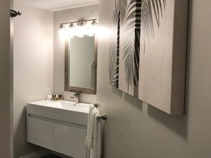 Une salle de bain avec un lavabo blanc, un miroir et un porte-serviettes.