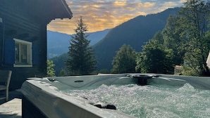 Ein Whirlpool mit Bergblick, umgeben von Bäumen und einer Holzhütte.