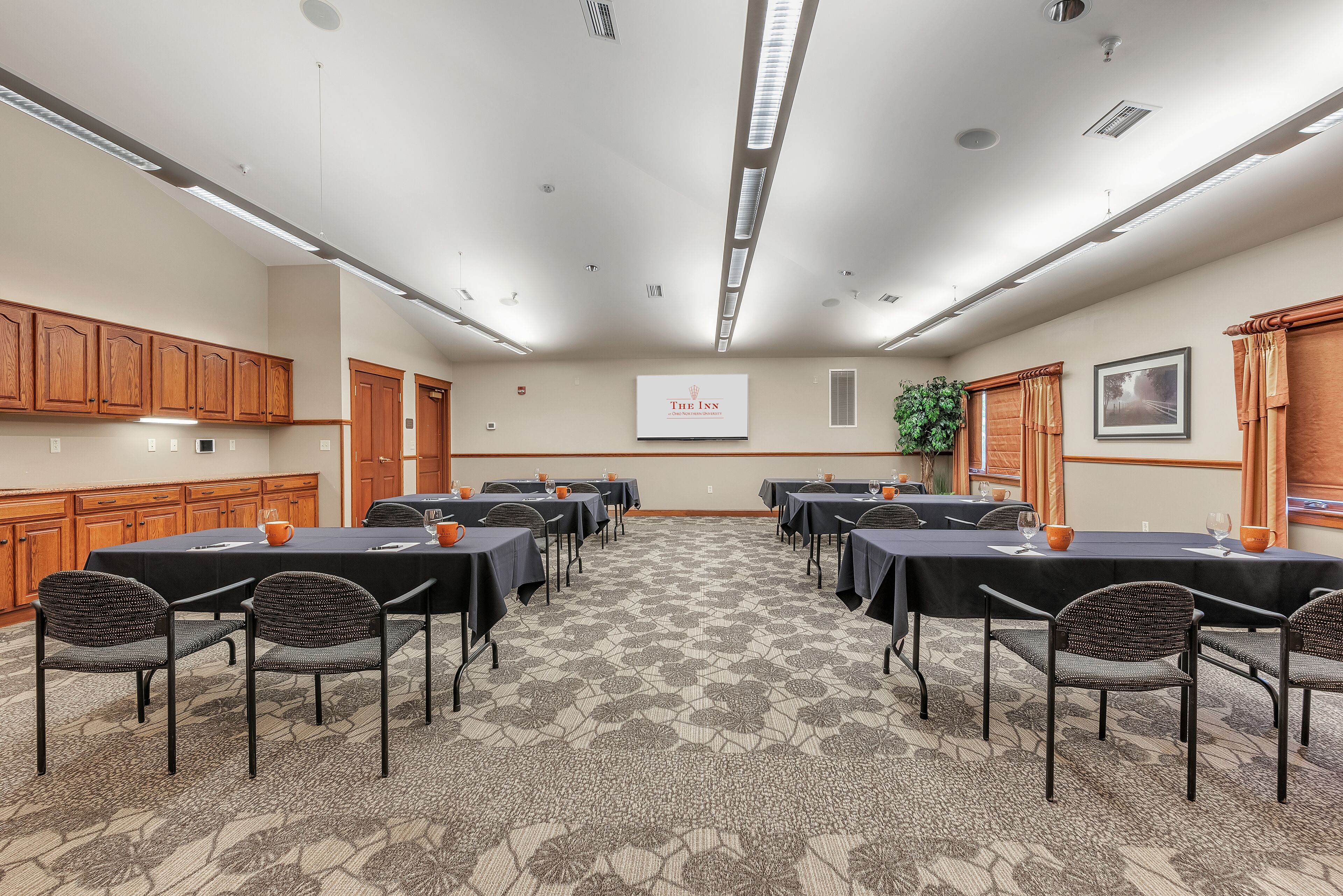 A conference room with a long table, chairs, and a projector screen displaying "The Inn".