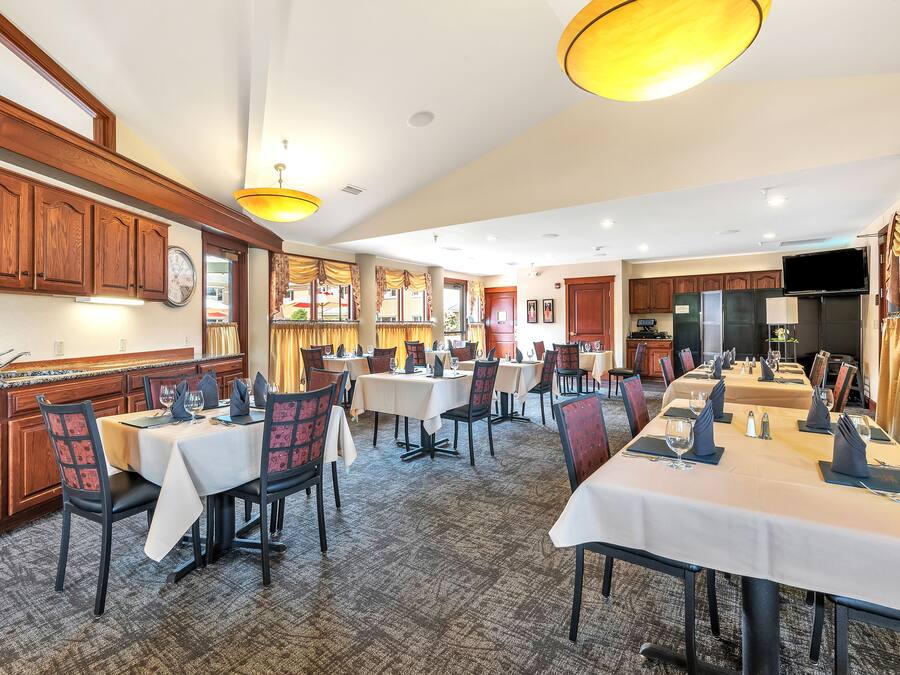 Een restaurant in een hotel, met meerdere tafels en stoelen, houten kasten en een klok aan de muur.