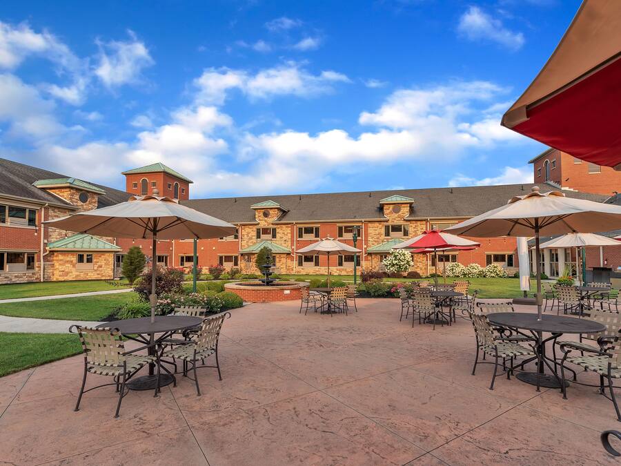 An outdoor patio area with tables and chairs, surrounded by brick buildings and a clear sky.