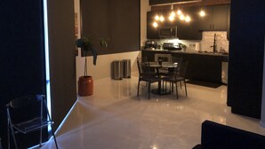 Una cucina moderna con mobili scuri, un'area pranzo con tavolo e sedie, e una pianta in vaso.