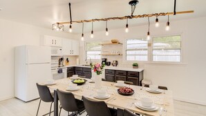 Una cucina moderna con mobili bianchi, un tavolo da pranzo per quattro persone e illuminazione a sospensione.