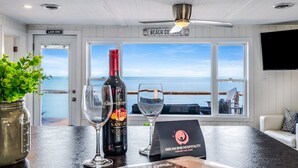 En bardisk med en vinflaska, glas, en meny och utsikt över stranden.