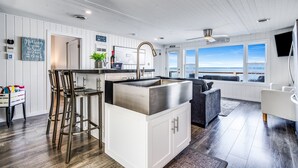Ett modernt kök med en stor köksö, barstolar och utsikt över havet.