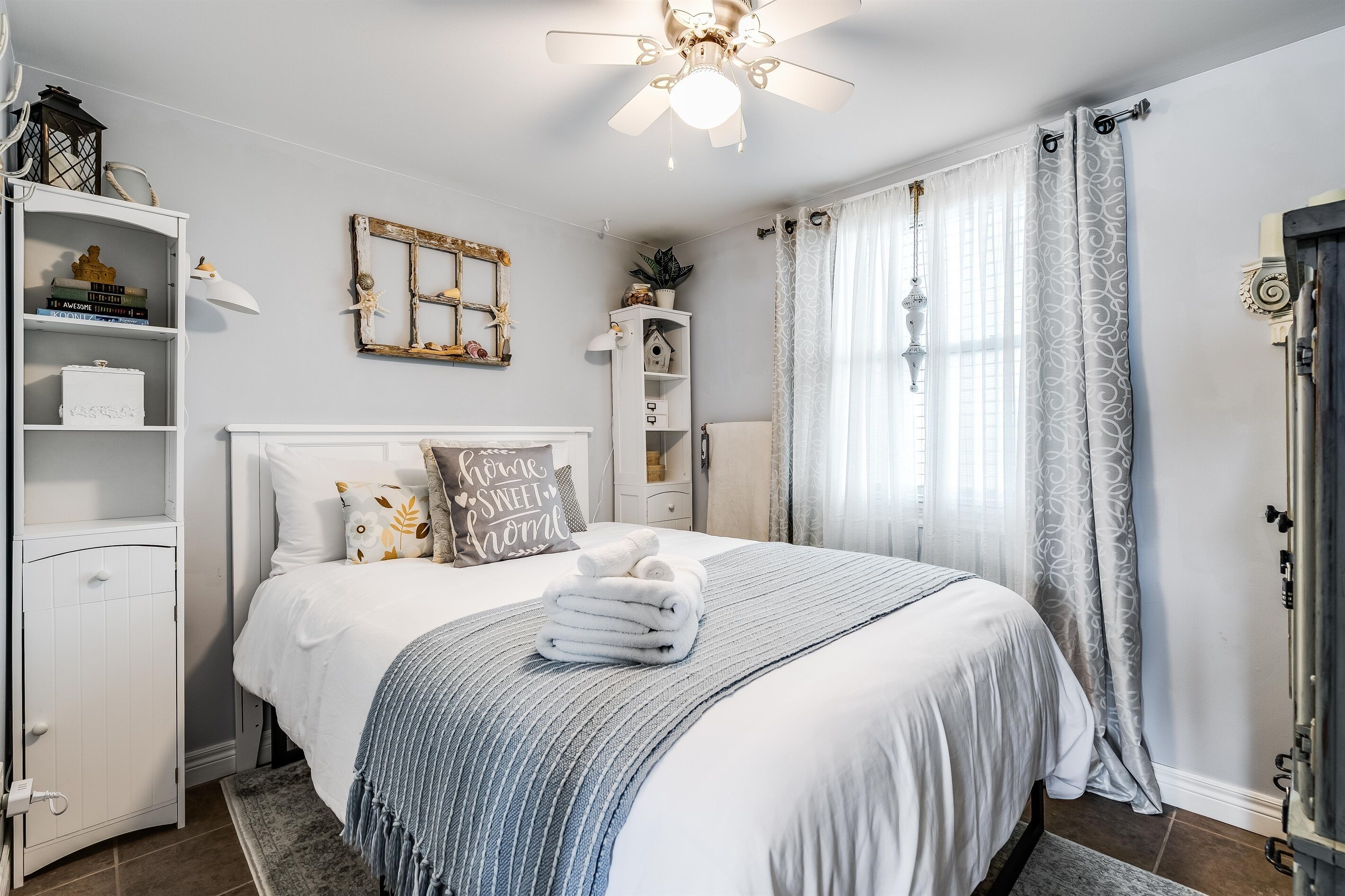 A neatly arranged bedroom with a bed, bedside tables, a wardrobe, and a ceiling fan.