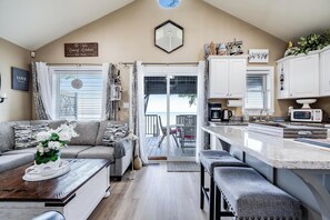 A cozy living room with a sofa, a coffee table, and a view of the outdoors. - Private Beach Escape | Sunset Views + Hot Tub (Leamington)