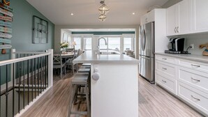 Une cuisine moderne avec des meubles blancs, un îlot central et un coin repas offrant une vue agréable.