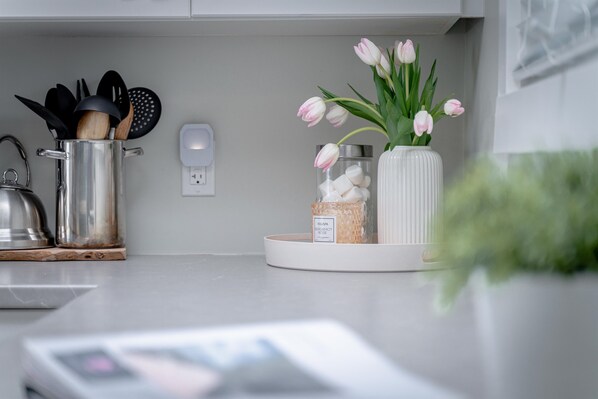 A kitchen counter with a pot, a jar of sugar, and a vase with tulips. - Point Pelee Water Access + Fire Pit | Sleeps 8 (Leamington)