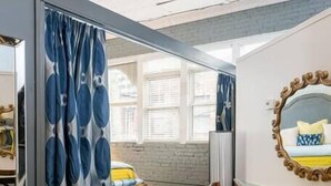 A modern bedroom with a large mirror, a cowhide rug, and a view of a cityscape through large windows. - 35 Carolina Lane  Loft Downtown on Historic Alley + One Free Off Street Parking (Asheville)