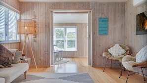 Una sala de estar moderna con paredes de madera, un sofá, una silla, una lámpara y una alfombra.