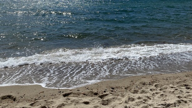 Een strand met heldere luchten en rustige golven.