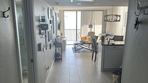 Un couloir qui donne sur un espace cuisine moderne, une table à manger et un canapé.