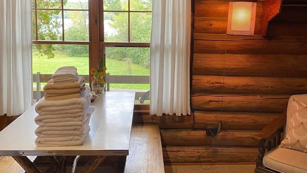 Interior rústico de una cabaña con una mesa de madera, un banco y una silla.