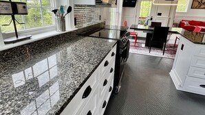 A modern kitchen with granite countertops, white cabinetry, and a large window.